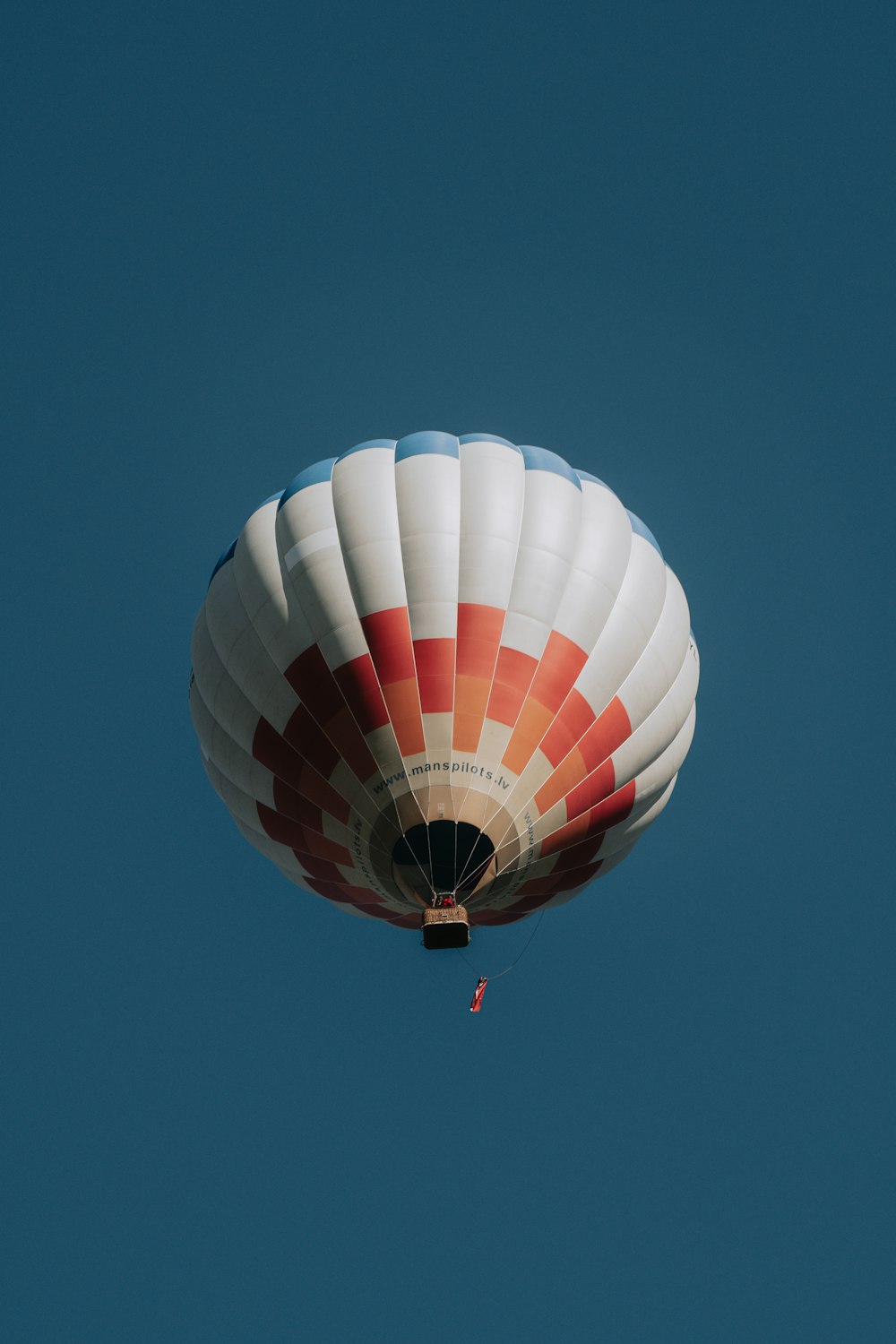 red white and blue hot air balloon in mid air under blue sky during daytime