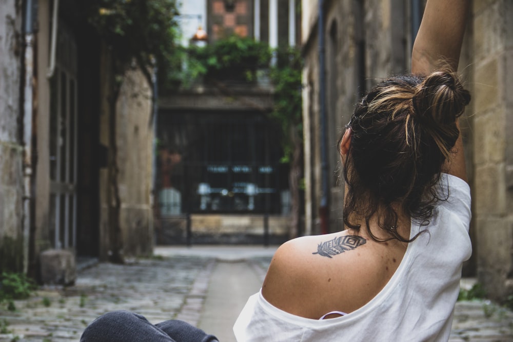 woman in white tank top sitting on concrete bench during daytime