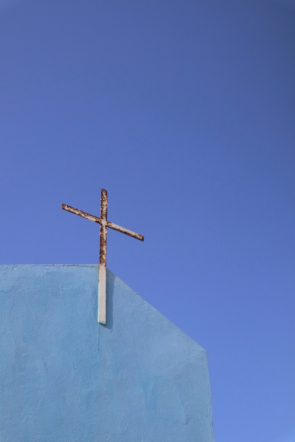 cruz de madera marrón sobre tela blanca bajo el cielo azul durante el día