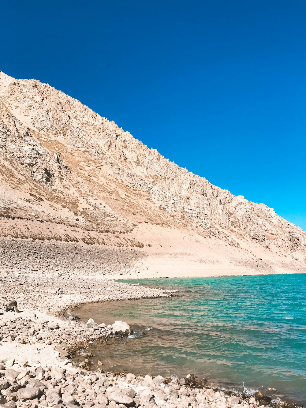 brown mountain near body of water during daytime