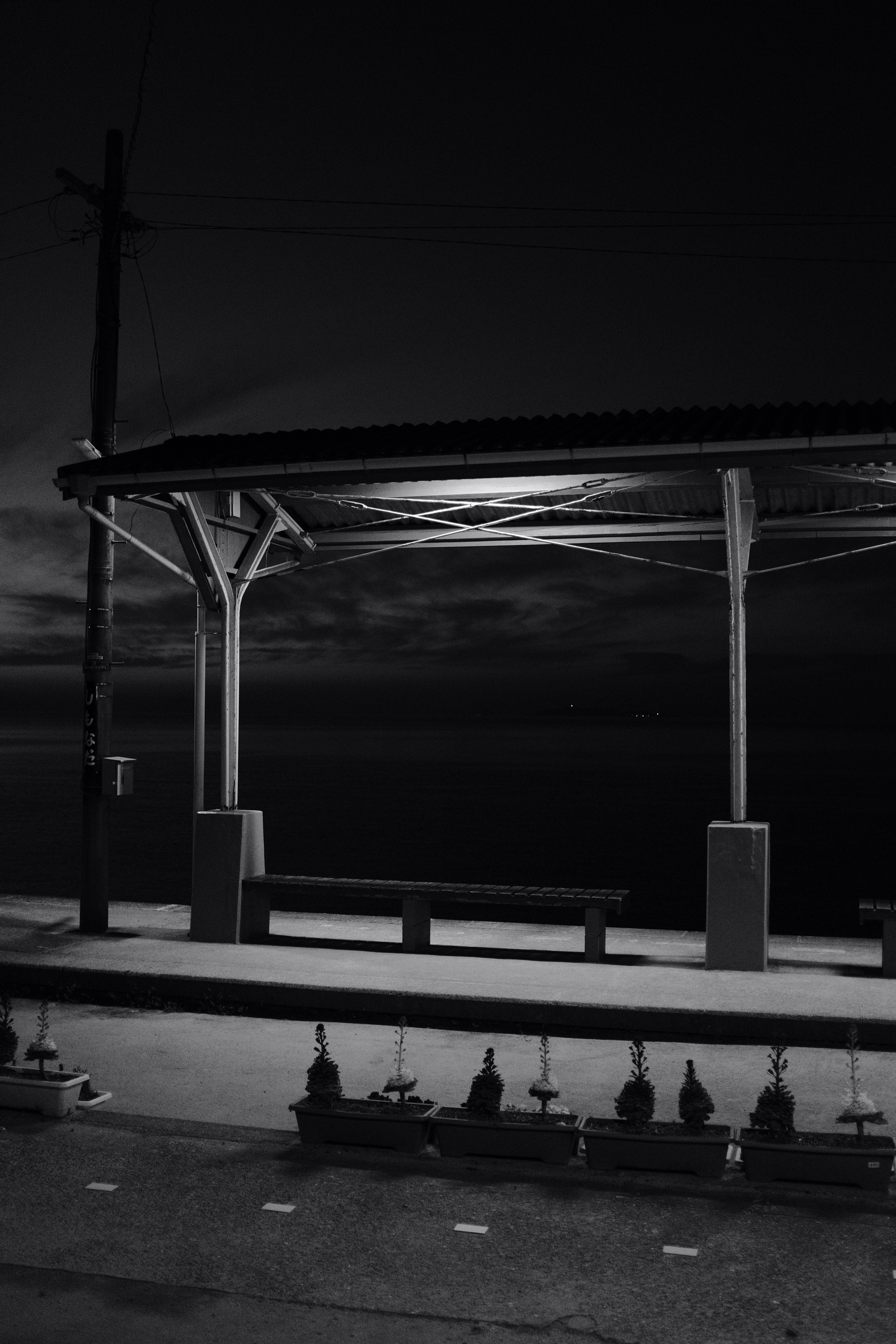 grayscale photo of people sitting on bench near body of water