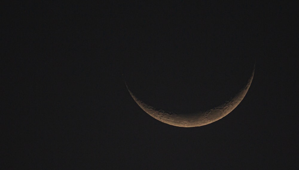 brown crescent moon in the sky