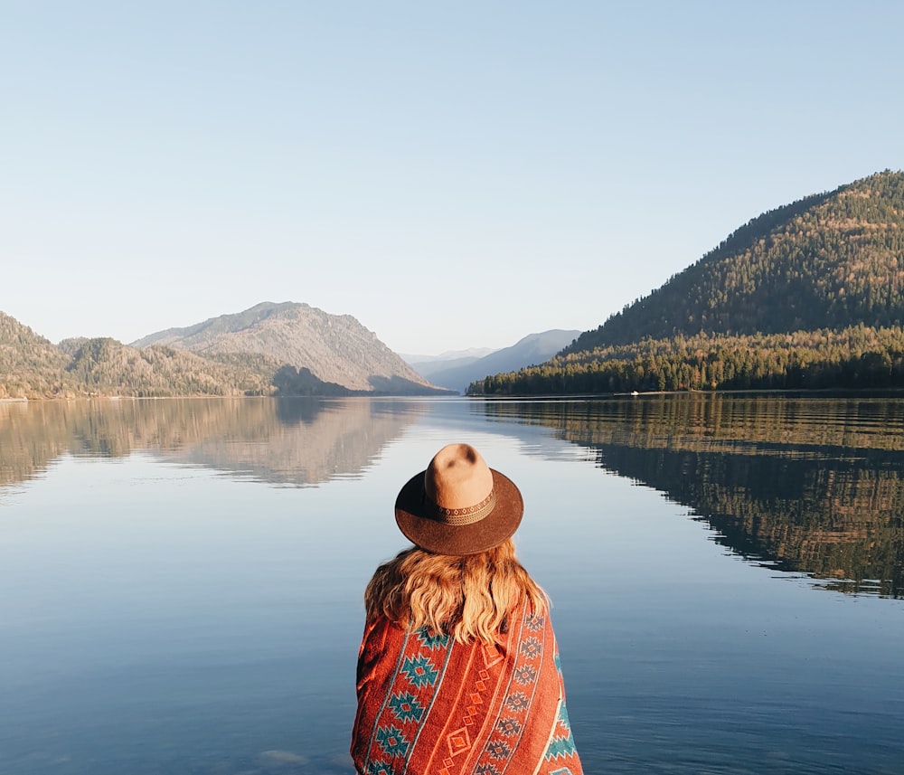 woman in blue and brown hijab standing near lake during daytime