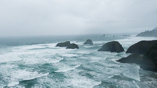 brown rock formation on sea under white clouds during daytime in Cannon Beach United States