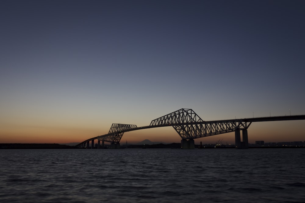 silhouette of bridge over the sea during sunset
