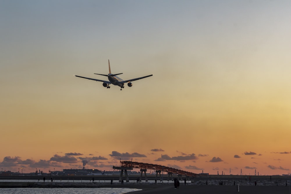 Silhouette des Flugzeugs, das bei Sonnenuntergang über die Stadt fliegt