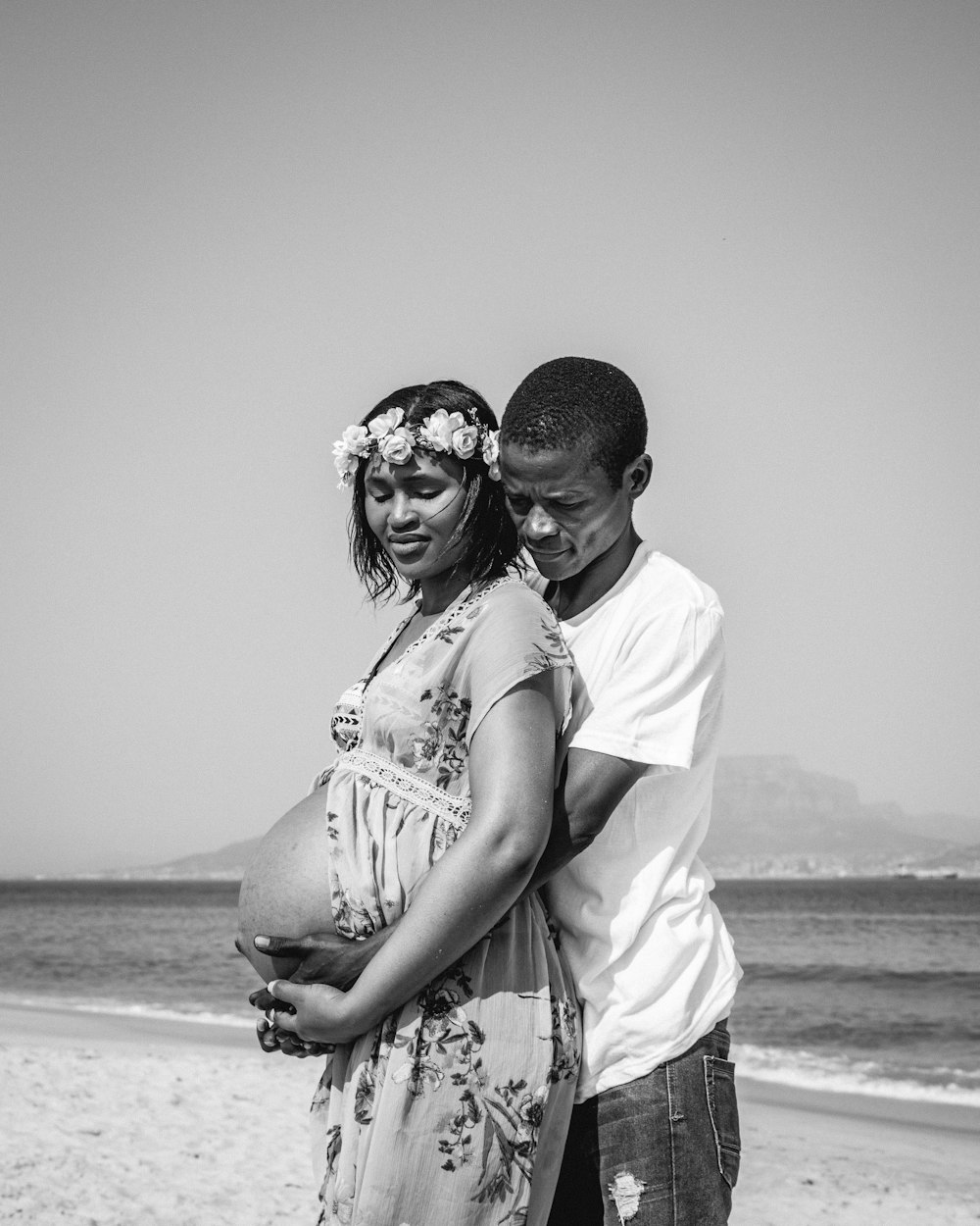 a man and woman standing on a beach next to the ocean