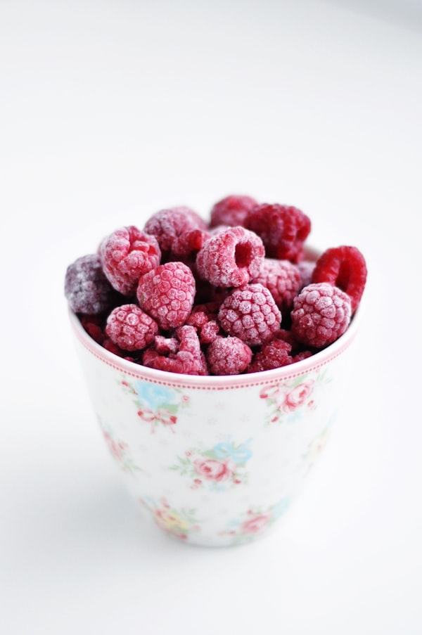A bowl filled with frozen raspberries symbolizing the concept of freezing eggs for fertility preservation.