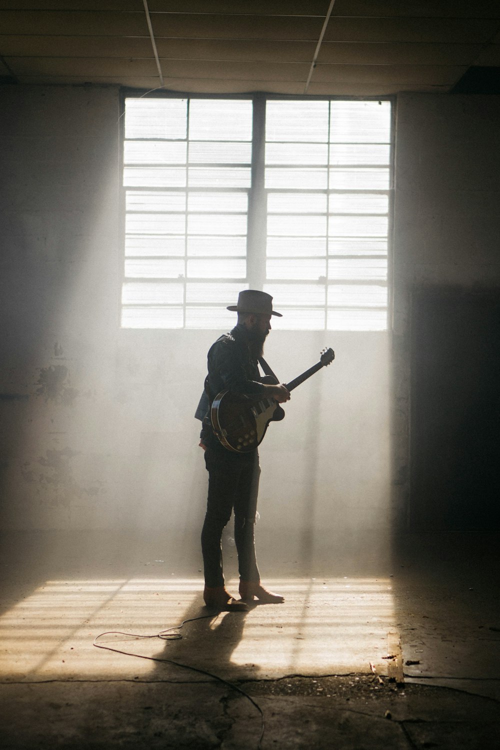 man in black jacket and brown pants playing guitar