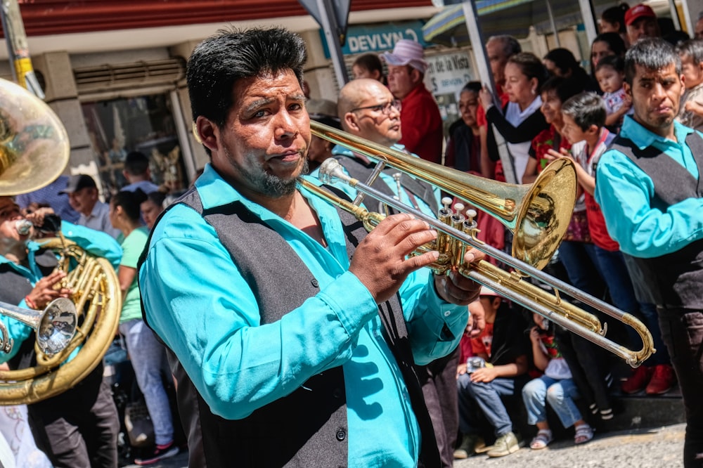 man in blue and black jacket holding brass trumpet
