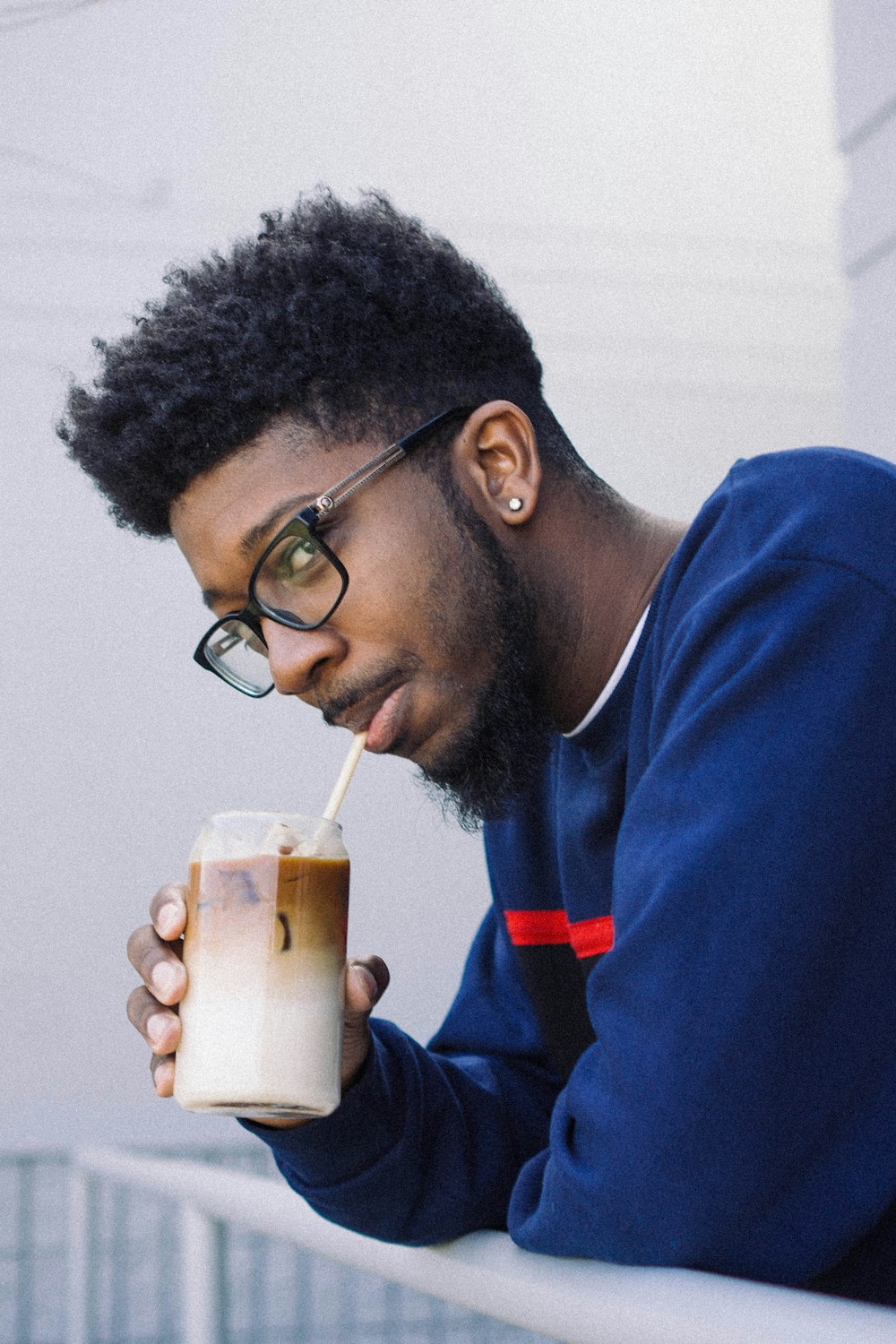 man in blue and red jacket drinking from white cup