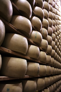 Cheese wheels stacked on a shelf in a factory.
