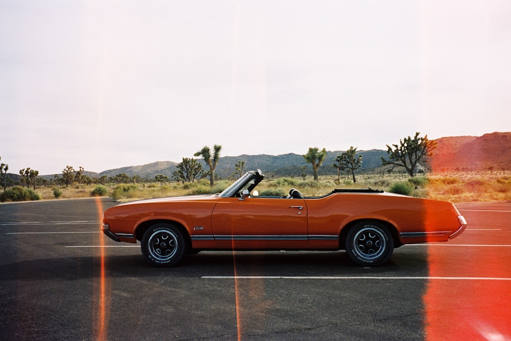 orange convertible car on gray asphalt road during daytime