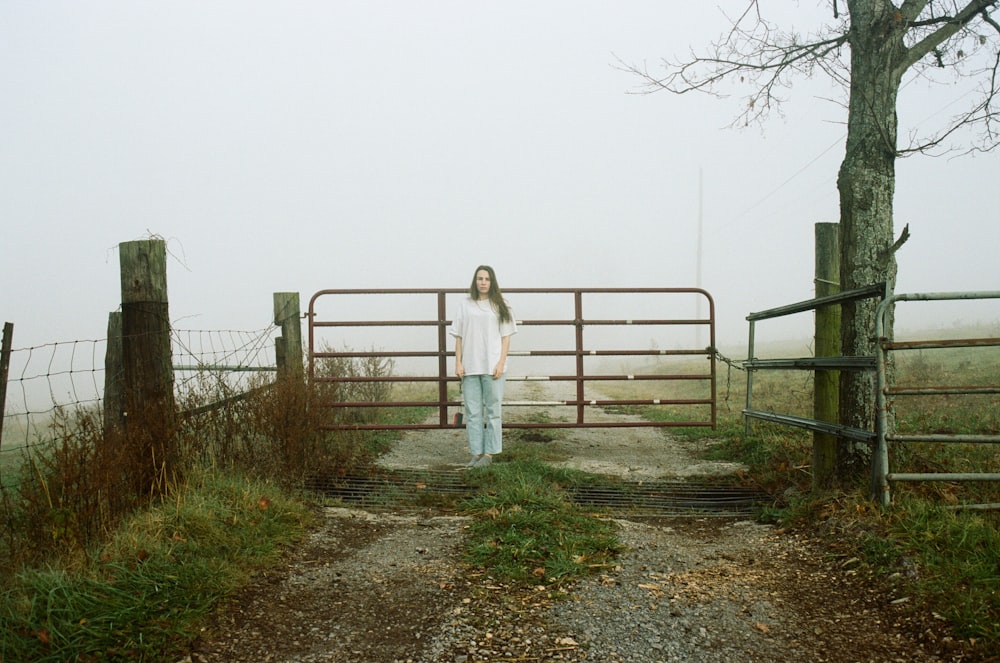 woman in white dress standing on brown dirt road