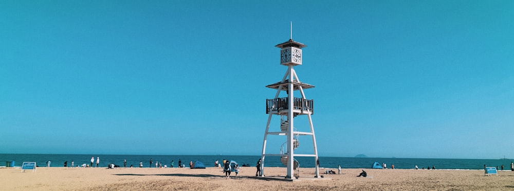 日中のビーチにある白と茶色の木製のライフガードタワー