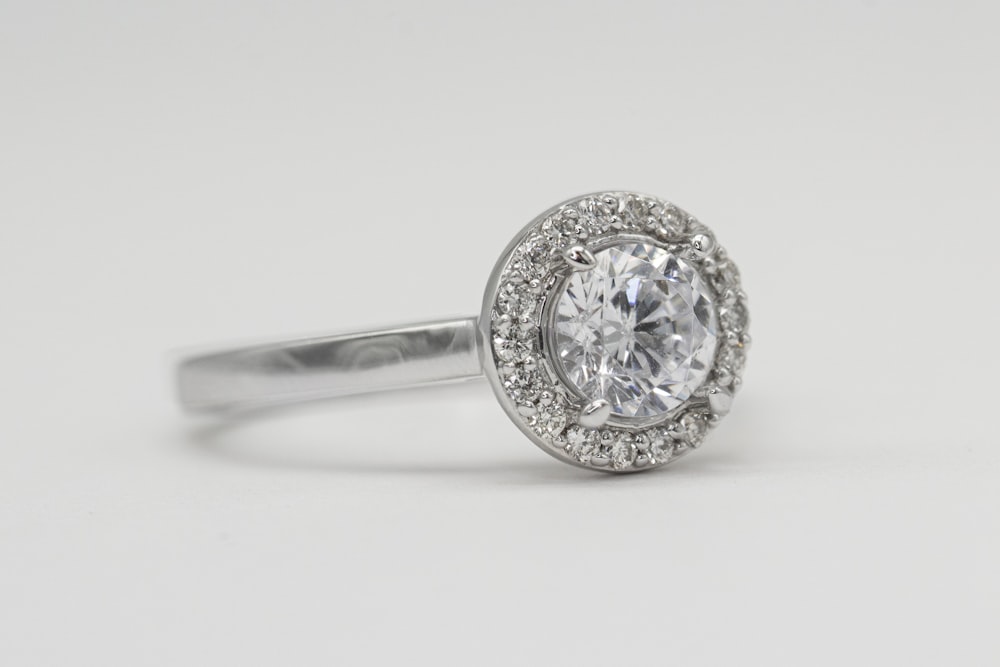silver diamond studded ring on white surface