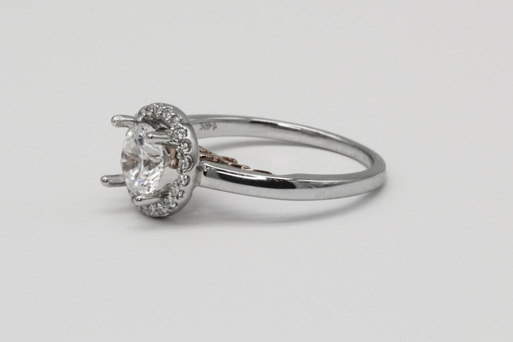 silver diamond ring on white surface