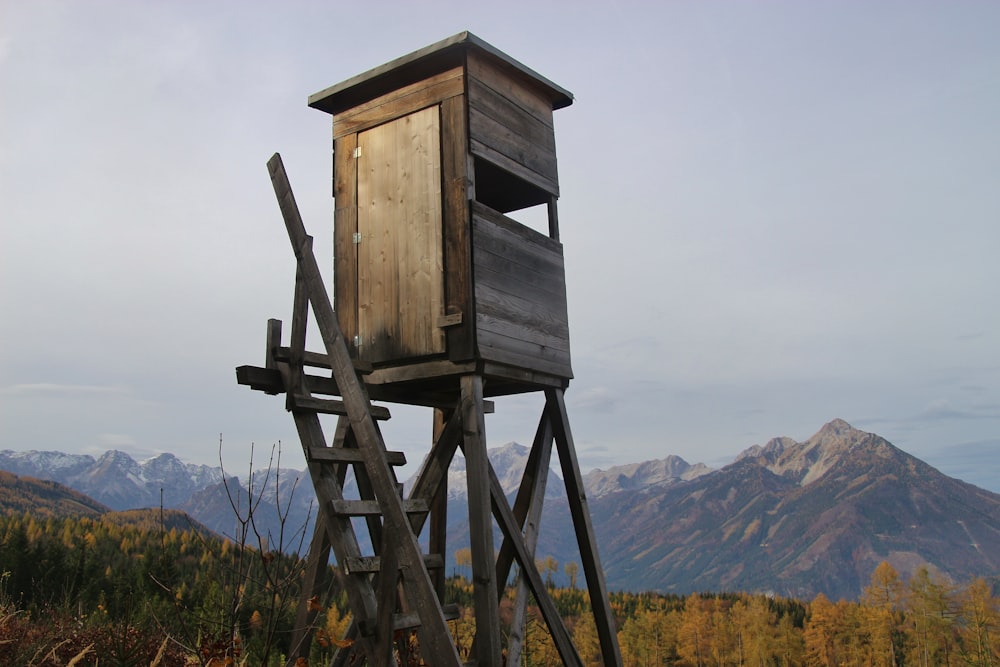 brown wooden lifeguard house on green grass field near mountain during daytime