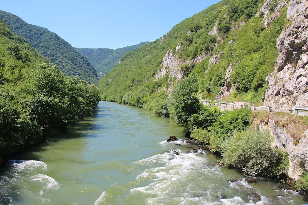 river between green mountains during daytime