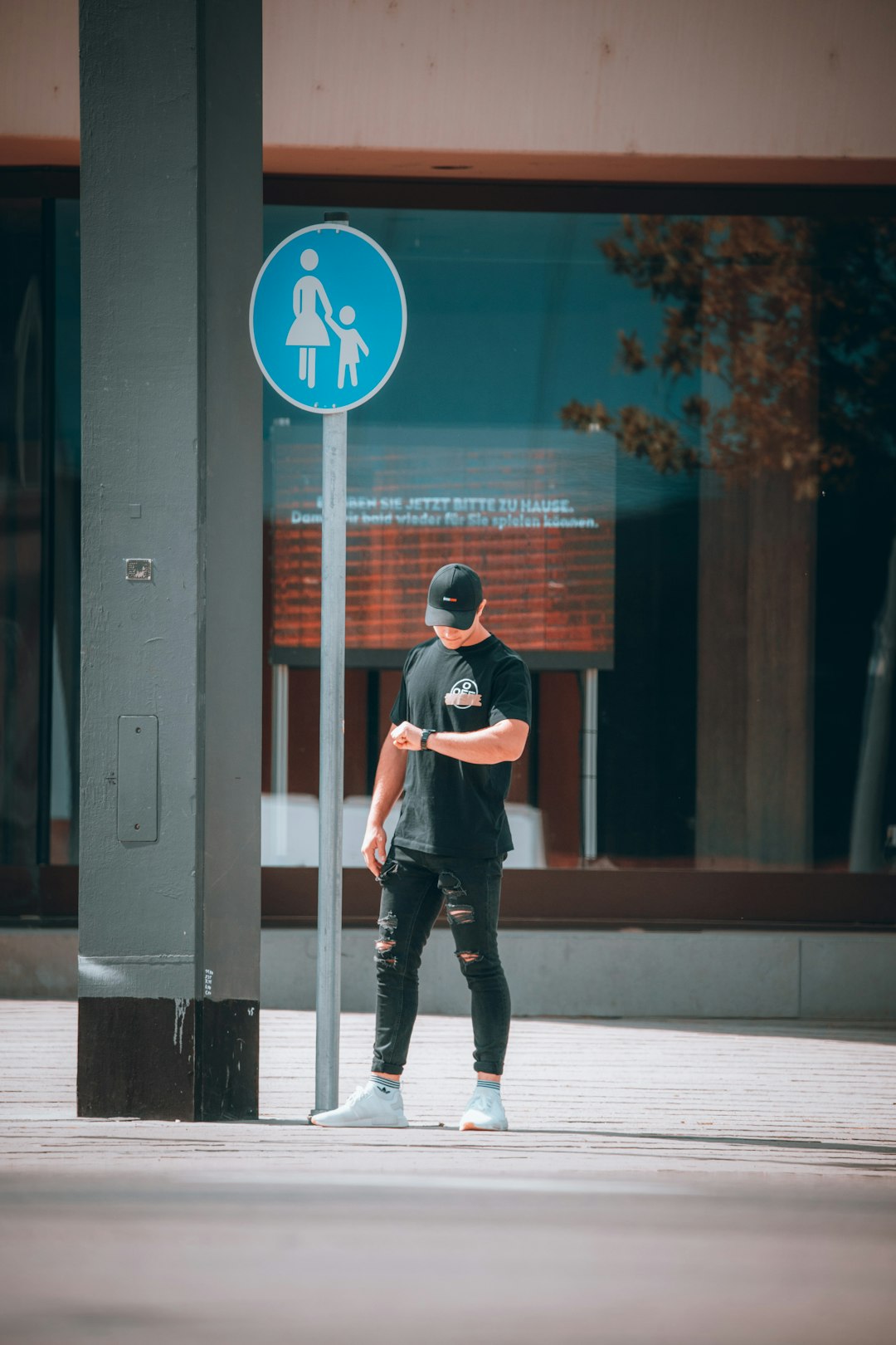 man in black t-shirt and black pants standing beside glass wall during daytime