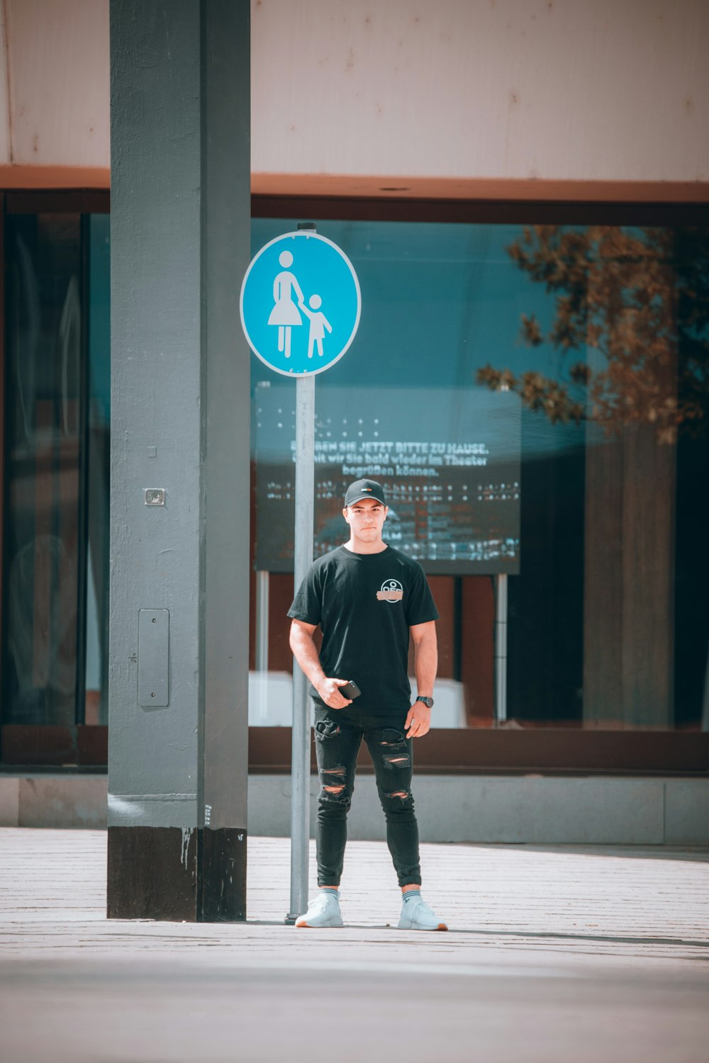 man in black crew neck t-shirt and black pants standing beside glass window