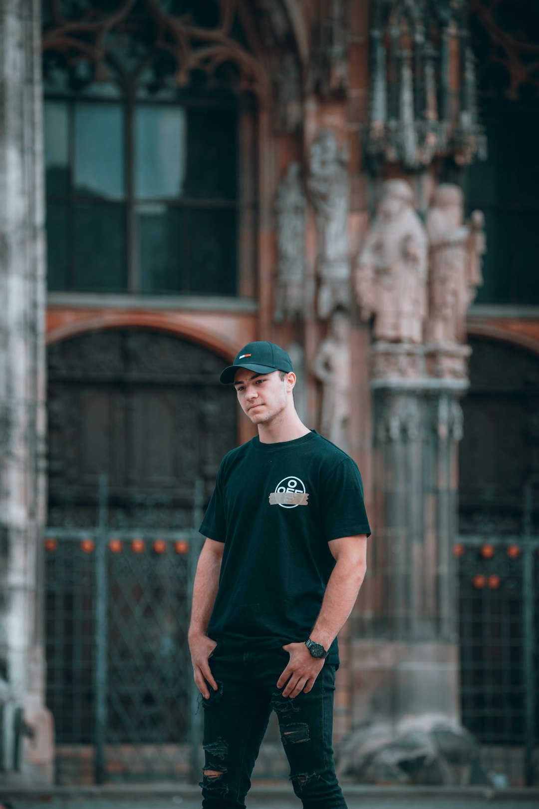 man in black crew neck t-shirt and orange fitted cap standing near building during daytime