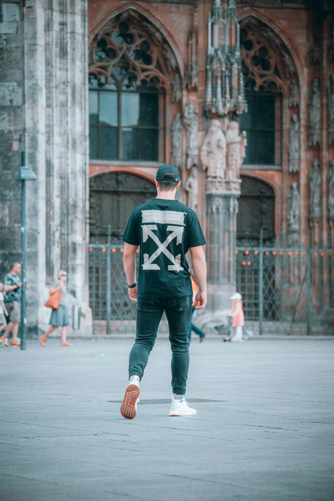 man in black and red crew neck t-shirt and blue denim jeans walking on street