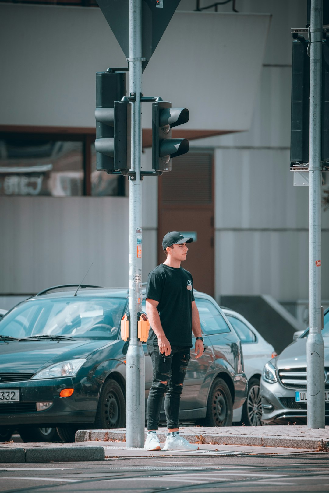 man in black t-shirt and black pants standing beside gray car during daytime