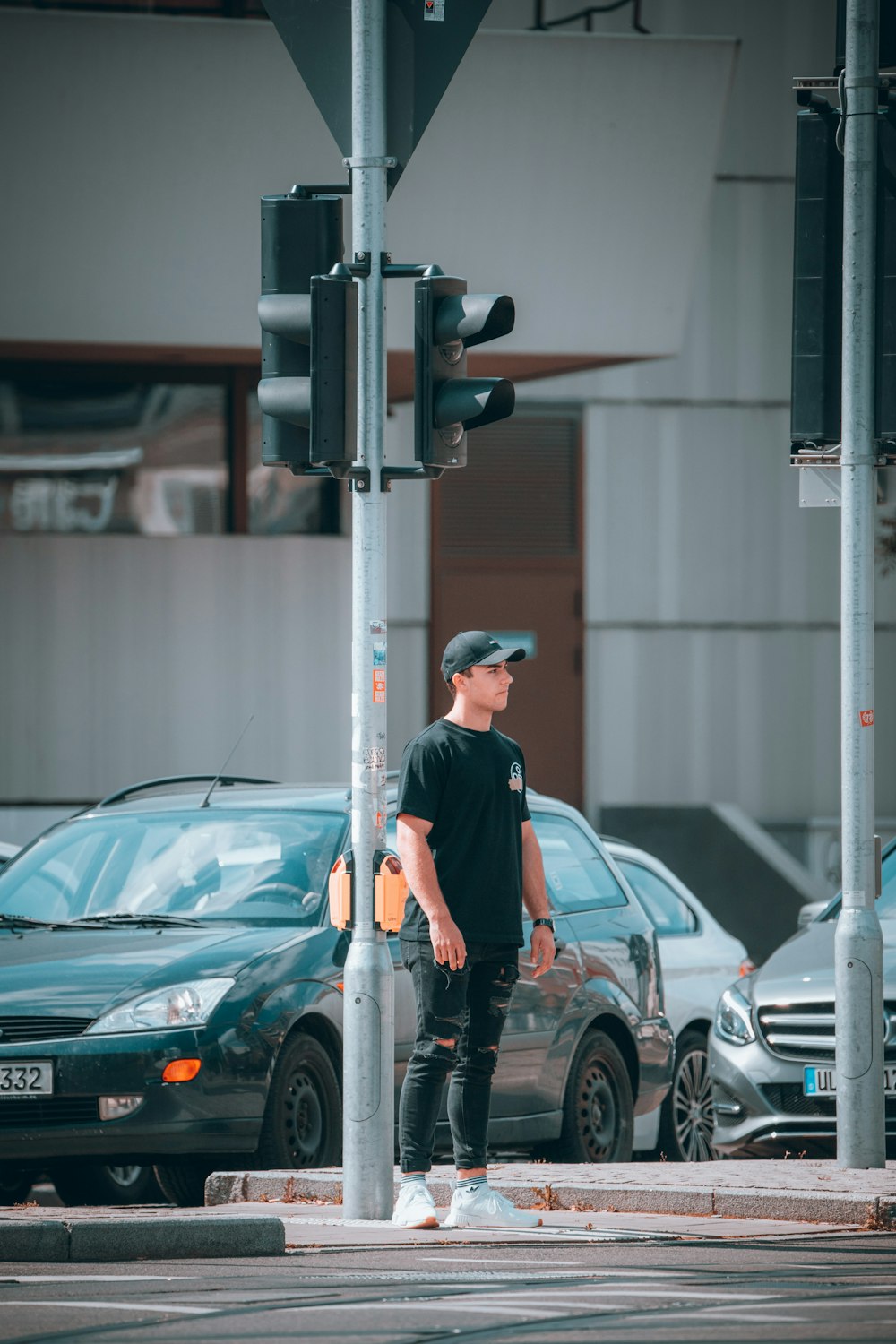 man in black t-shirt and black pants standing beside gray car during daytime