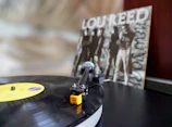 Vinyl record spinning on a turntable with Jaiden’s album cover subtly reflected in the background.