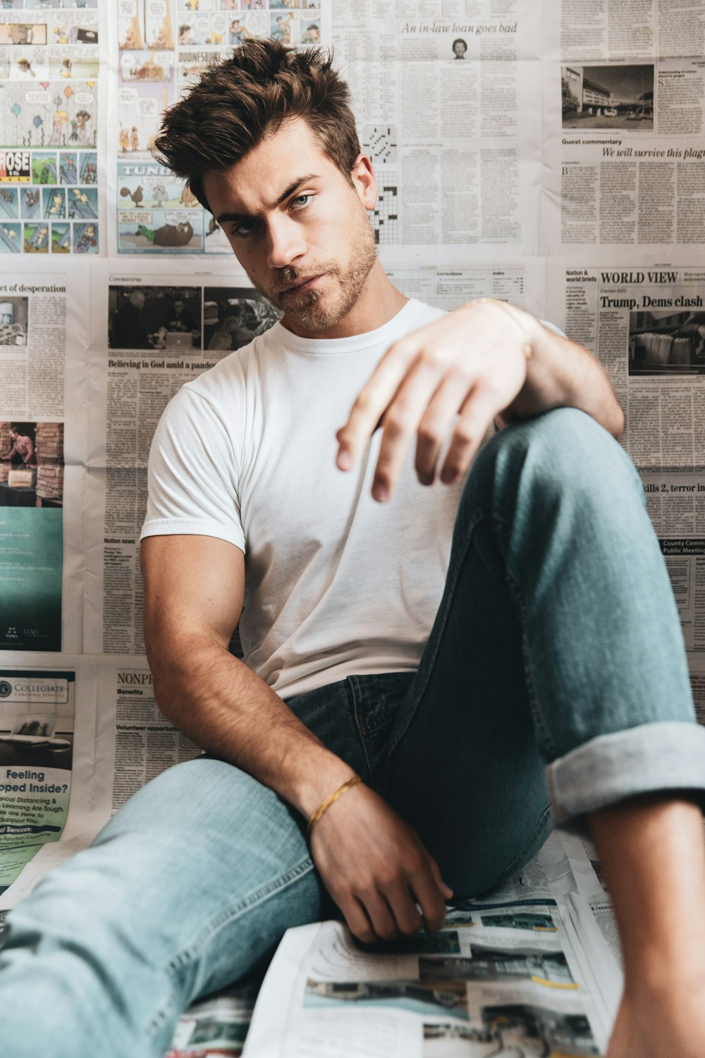 man in white crew neck t-shirt and blue denim jeans sitting on gray sofa