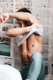 man in white shirt and blue denim jeans holding white textile