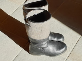 A pair of stylish long boots placed on a wooden floor.
