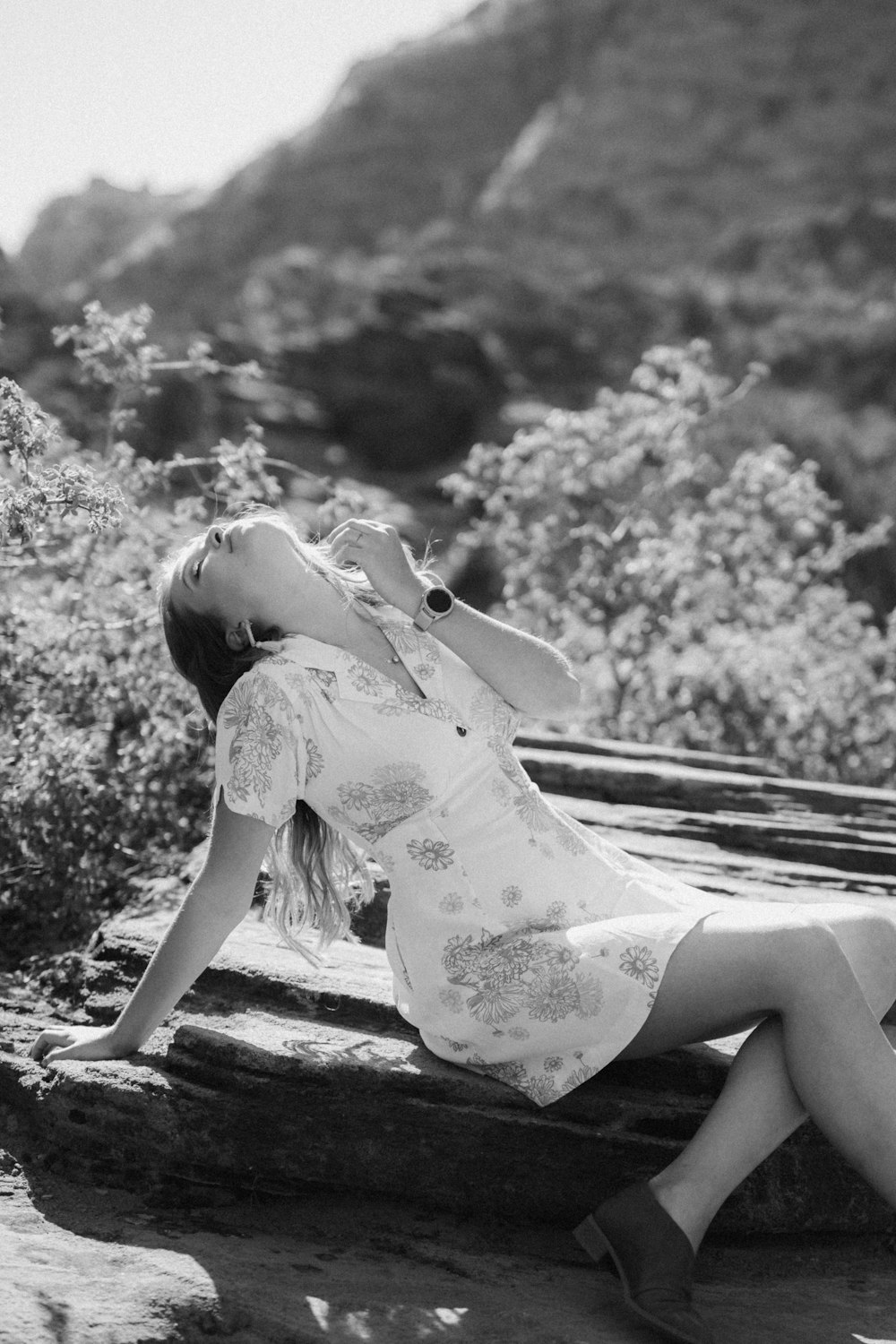 grayscale photo of girl in floral dress sitting on wooden bench