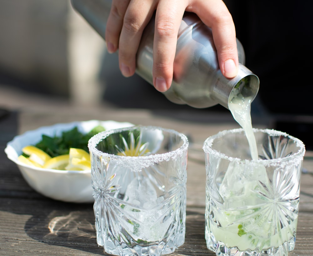 person pouring water on drinking glasses