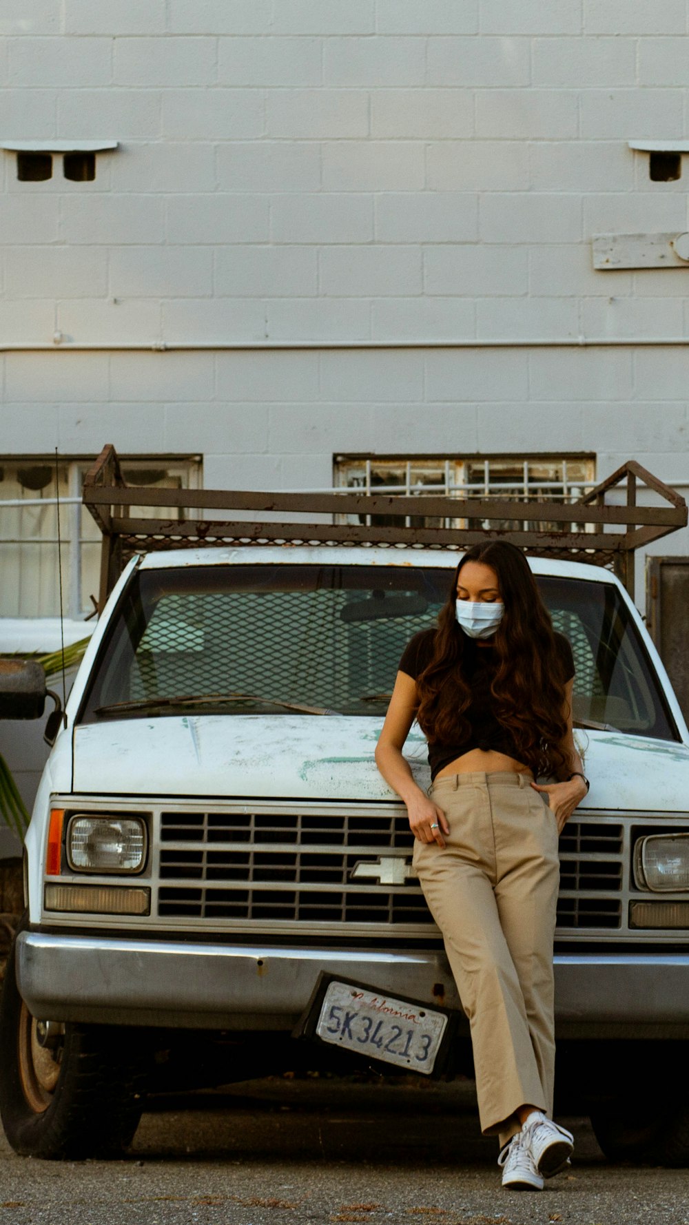 woman in black shirt and brown pants leaning on white mercedes benz car