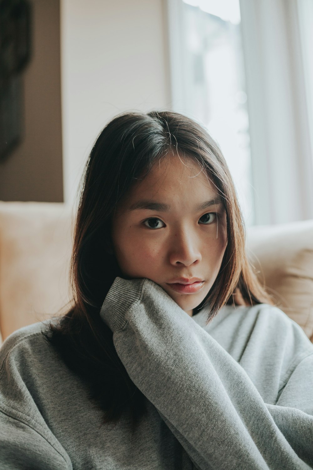 girl in gray sweater sitting on white couch