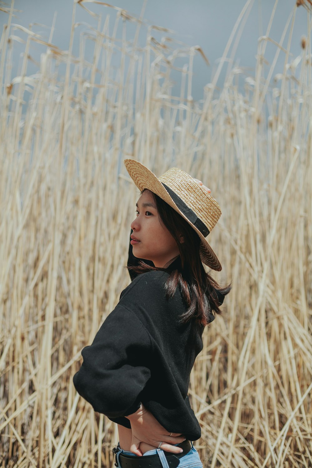 woman in black jacket wearing brown straw hat standing on wheat field during daytime