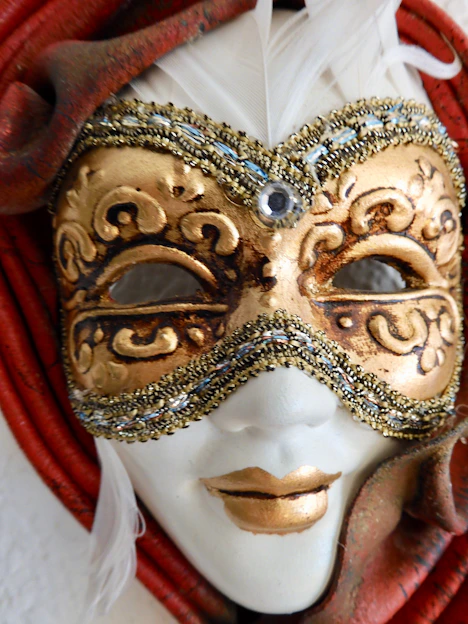 Close-up of a Mahalakshmi face mask adorned with pearls and colorful stones, glowing softly against a warm background.
