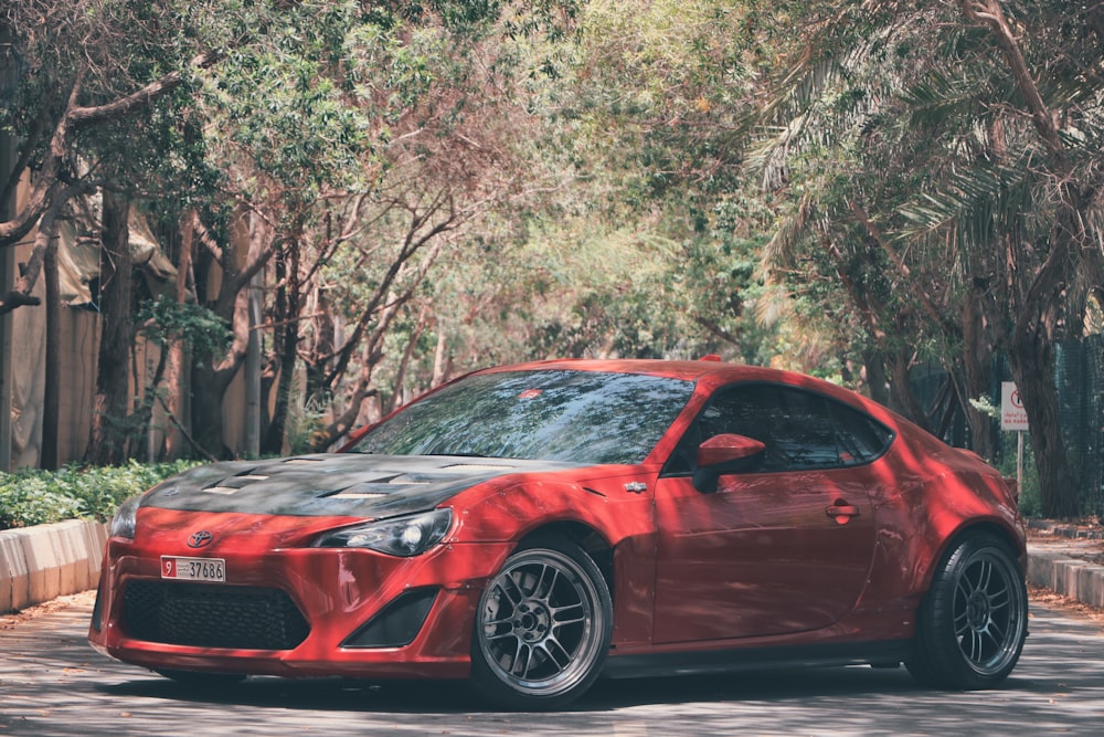 red audi coupe parked near green trees during daytime