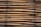 A stack of bamboo poles closely bound together, displaying a natural and earthy texture. The bamboo is arranged horizontally and tied with dark twine at intervals.