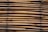 A stack of bamboo poles closely bound together, displaying a natural and earthy texture. The bamboo is arranged horizontally and tied with dark twine at intervals.