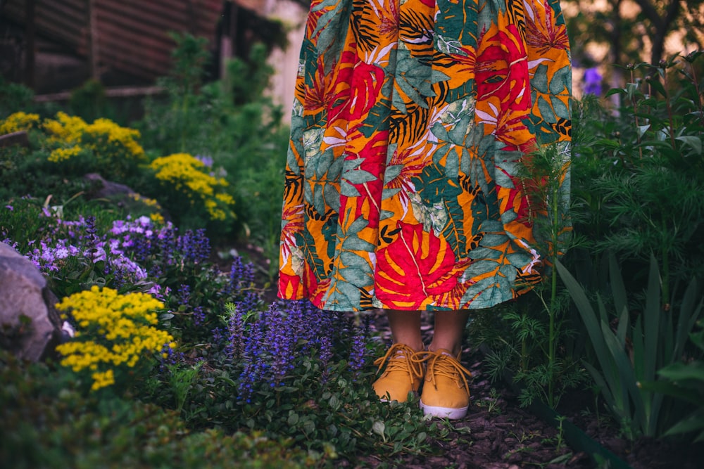 woman in orange and blue floral dress standing on yellow flower field during daytime