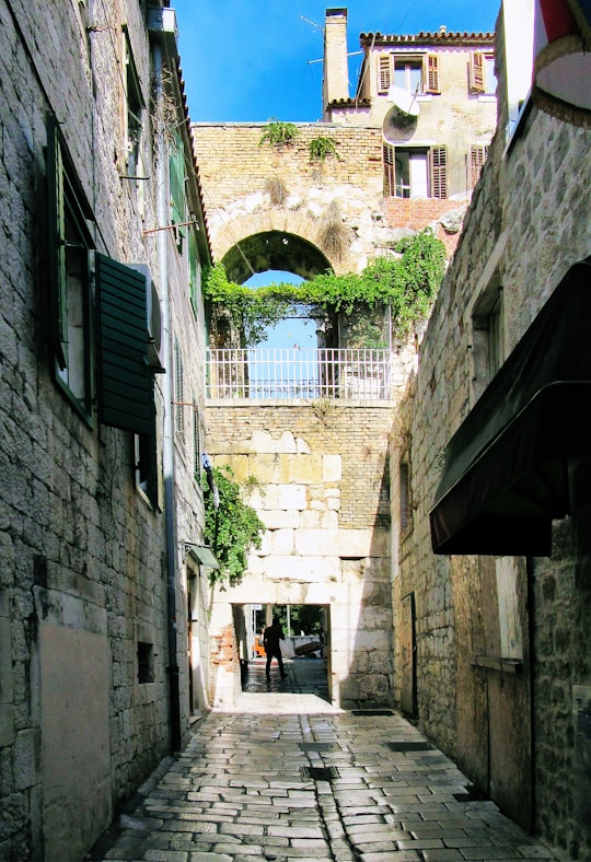 person in black jacket walking on hallway during daytime in Diocletian's Palace Croatia