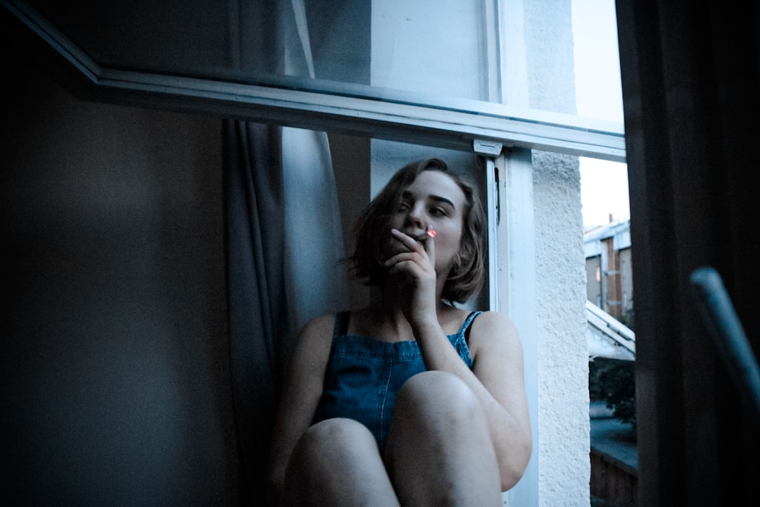woman in blue tank top sitting on window