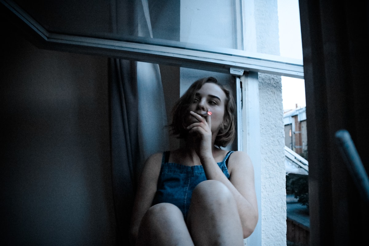 Woman in blue tank top sitting on window