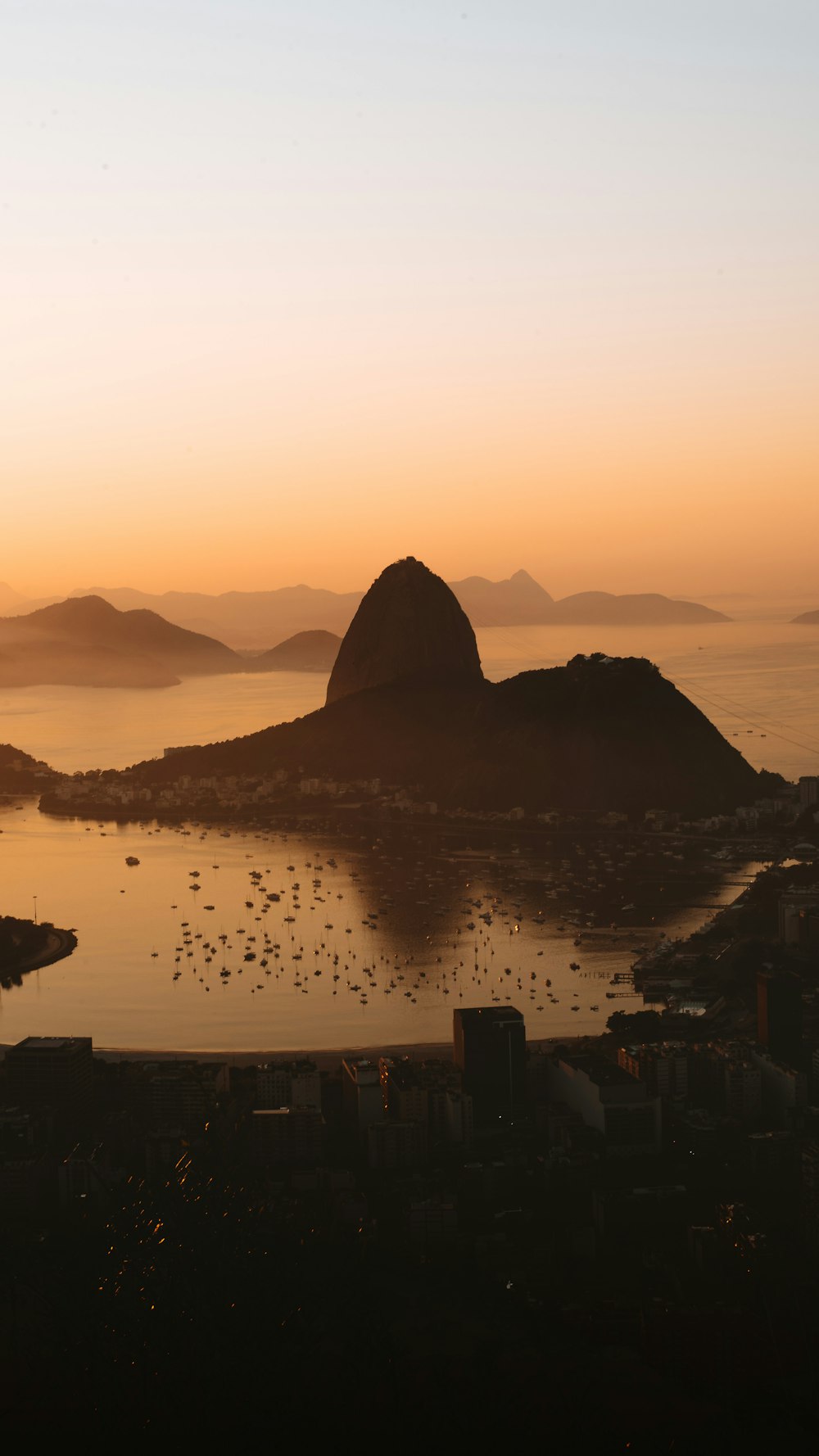 silhouette of mountain near body of water during sunset