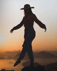 A graceful silhouette of a woman enjoying a serene sunset over the snowy Manali hills.