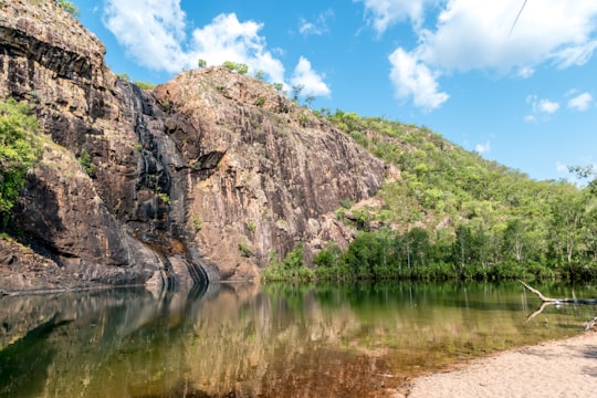 green and brown mountain beside river under blue sky during daytime in Kakadu NT Australia