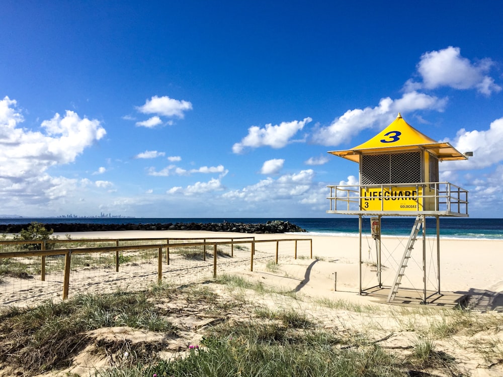 casa de playa de madera marrón en arena marrón cerca del mar bajo el cielo azul durante el día